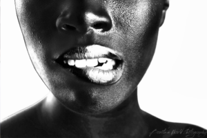 High contrast black and white photo of the lower half of a black womans face with metallic lip makeup