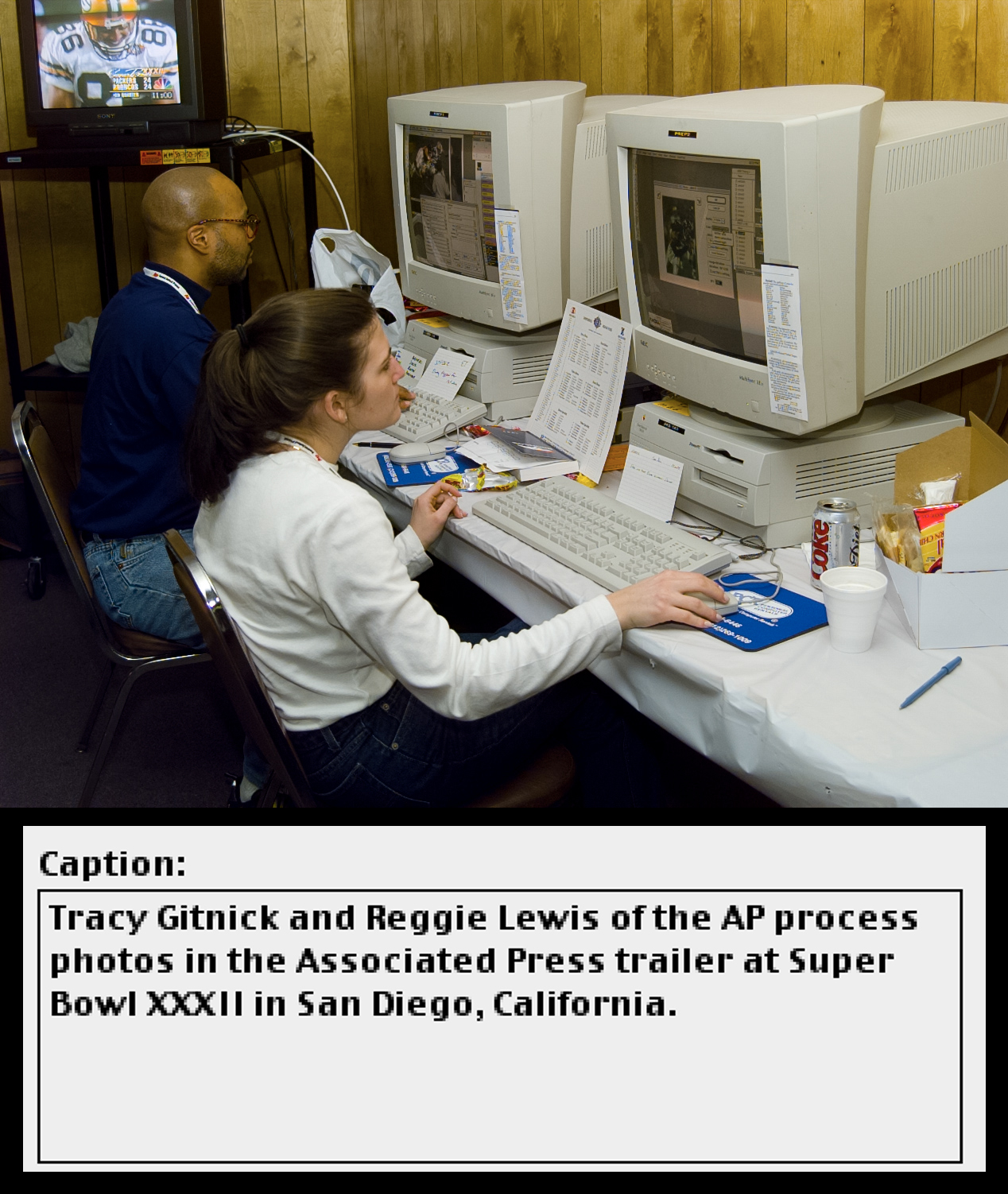 Two people sit at large computer workstations