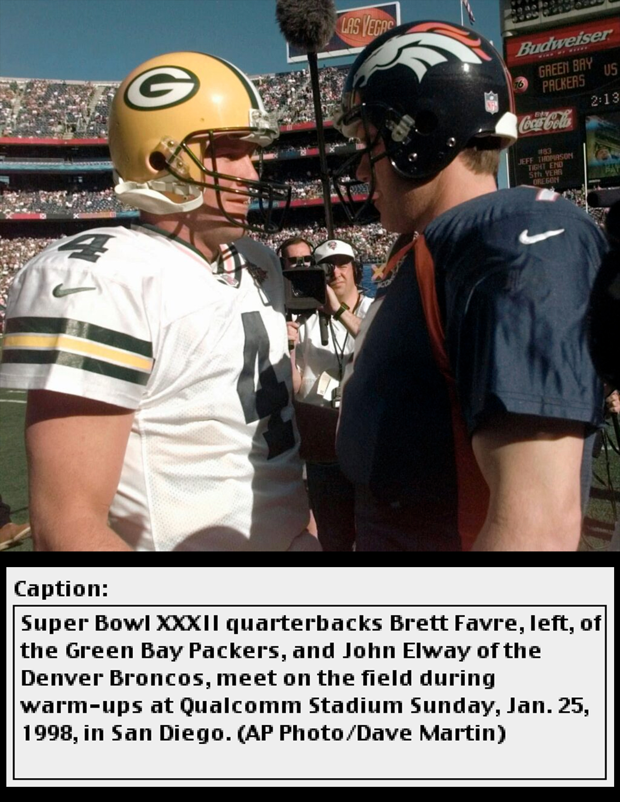 Two American football players in uniform in a stadium under a blue sky greet each other